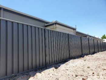 Newly installed grey Colorbond fence in a residential property backyard in Wollongong NSW.